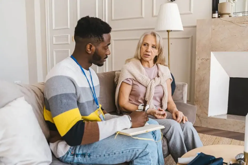 Volunteer talking with an elderly woman during a home visit