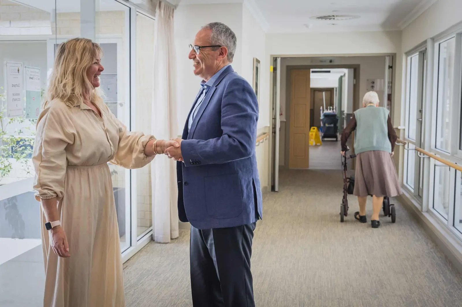 Lewis Chiat greeting a family member in an aged care home corridor