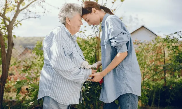 A younger woman and her elderly mother in a garden