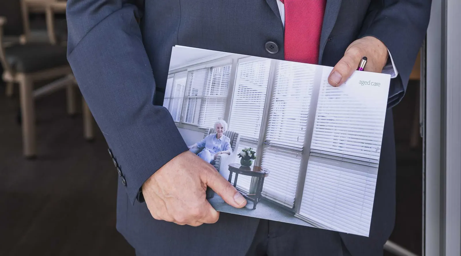 Lewis Chiat holding a brochure for an aged care home