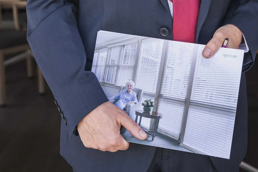 Lewis Chiat holding a brochure for an aged care home